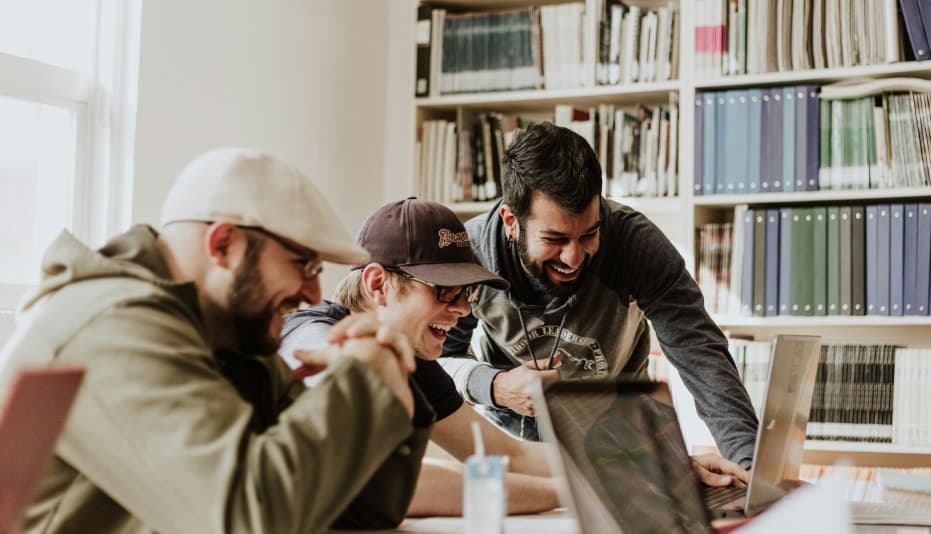 Group of males gathered around laptops