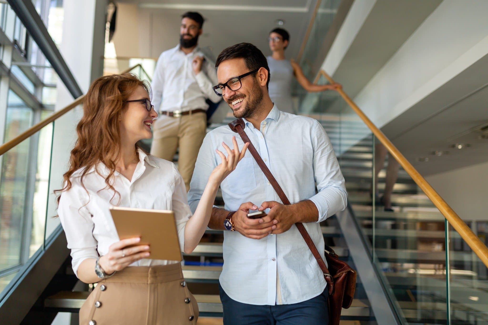 A man and a woman smiling an talking on an office stairway