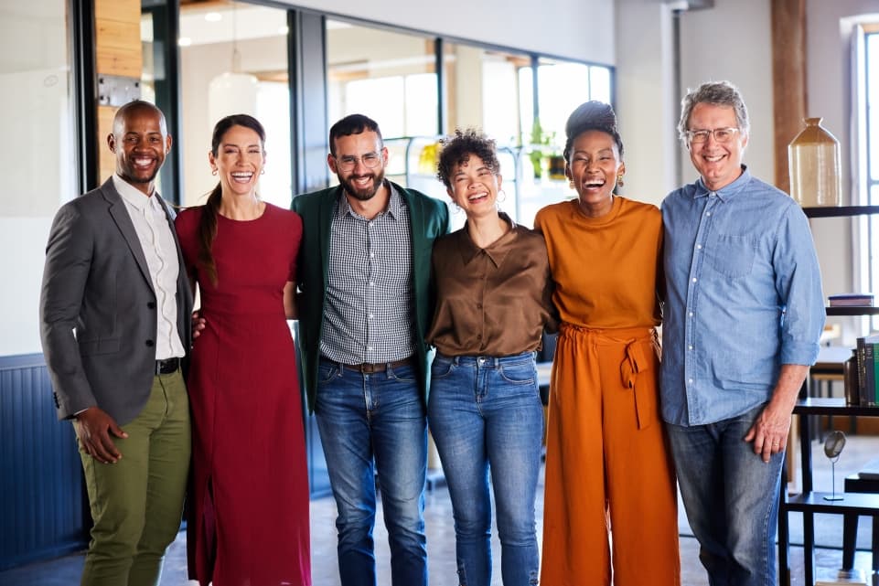 Group of six diverse colleagues laughing while posing together