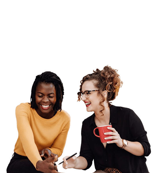 Two smiling women collaborating at their desk