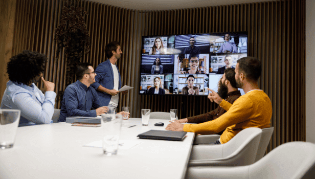 Colleagues in a conference room looking at large Teams screen collaborating across time zones