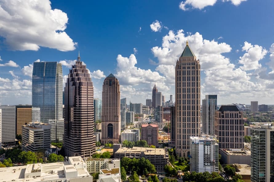 Atlanta skyline with skyscrapers visible in a blue sky with puffy white clouds